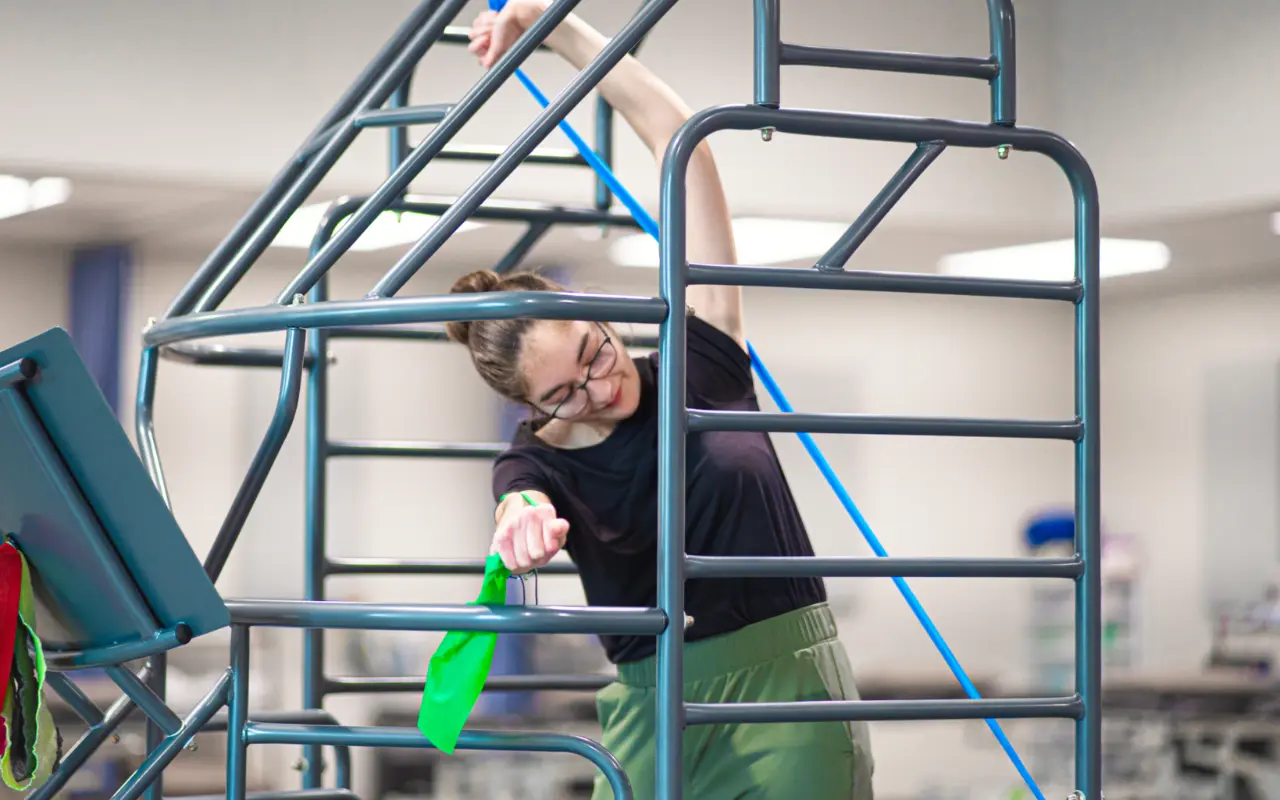 A teen stretching in a stretch cage to help improve her scoliosis.