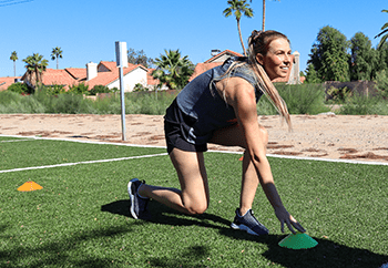 A woman doing ice skaters as she taps a green dome.