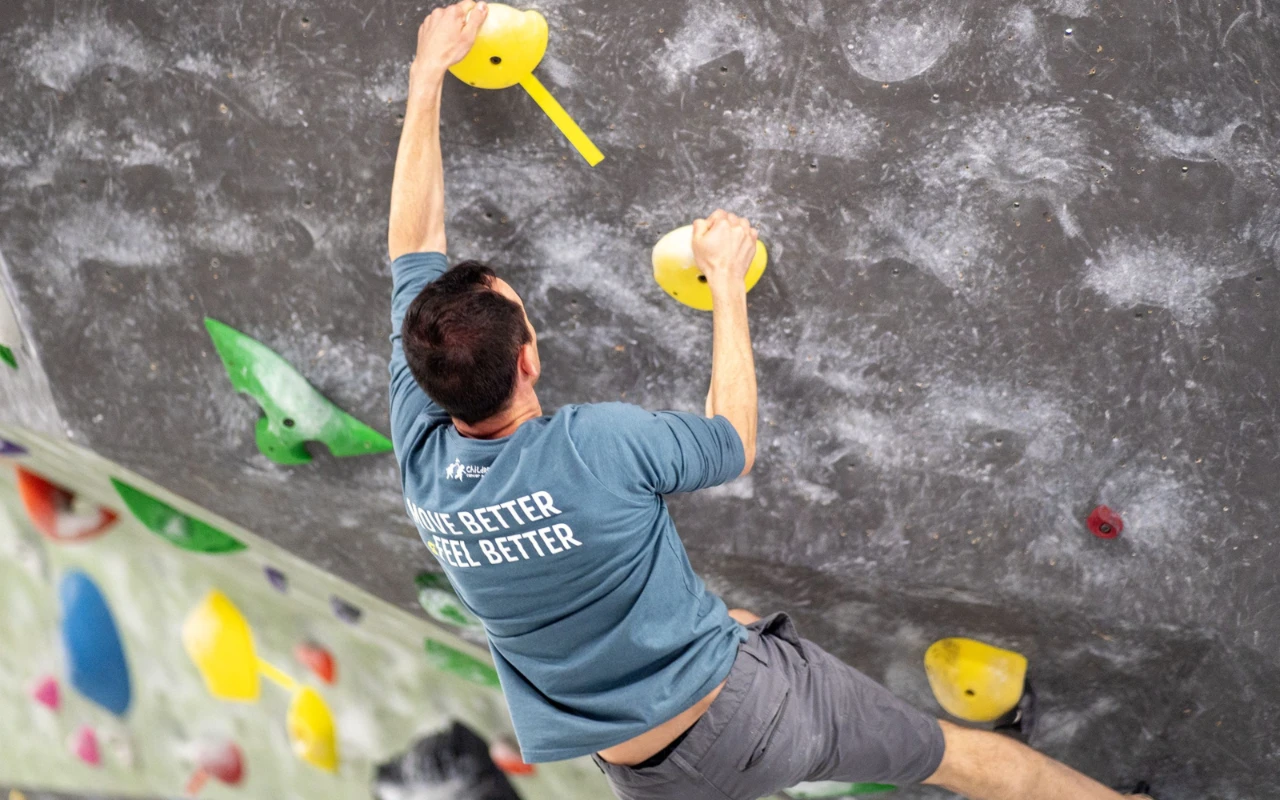 Derrick Debenedetto climbing an indoor rock wall.