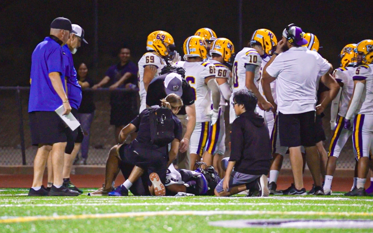 A football player lying on the ground as he gets treatment from emergency response teams after suffering from a concussion.
