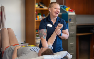 A hand therapist working on the shoulder of a patient laying down on a table.