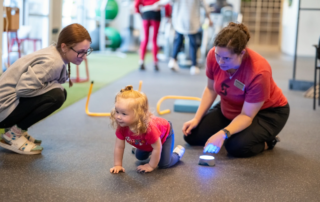 A therapist on the floor with a toddler.