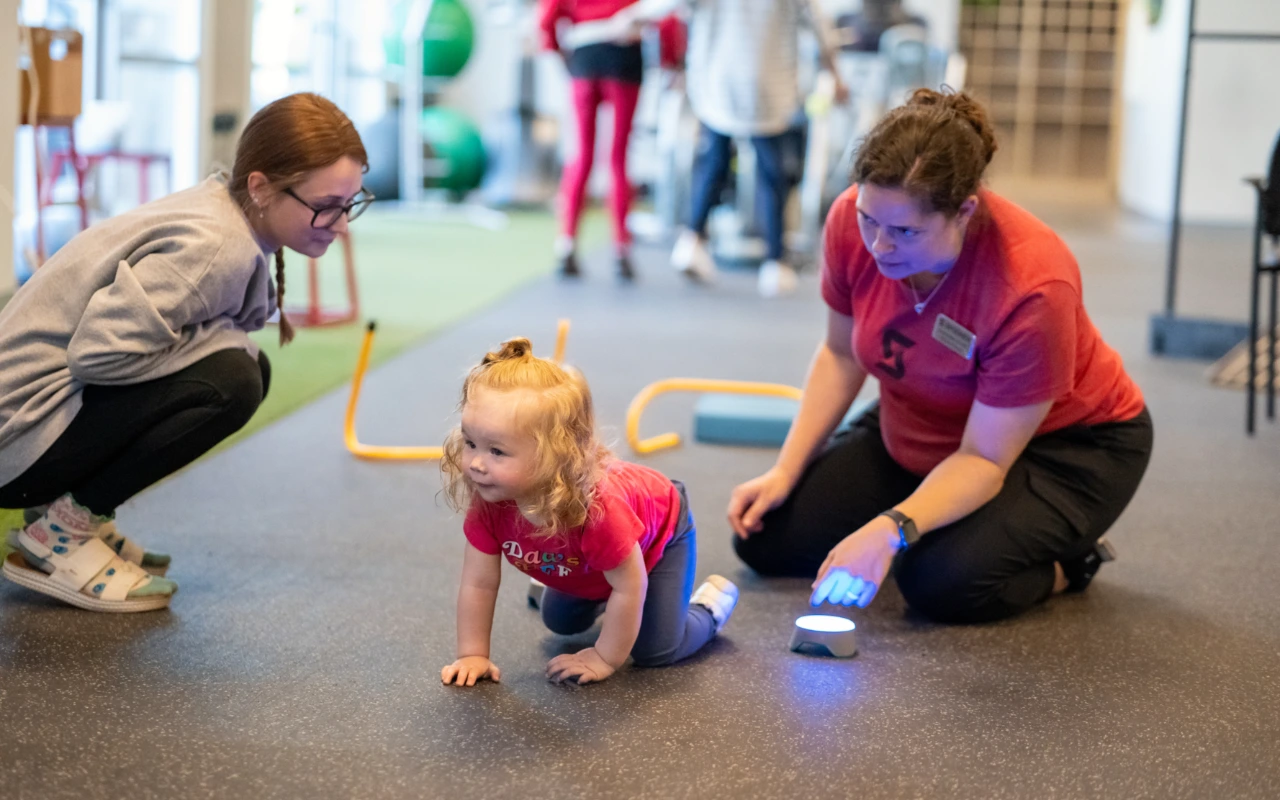 A therapist on the floor with a toddler.