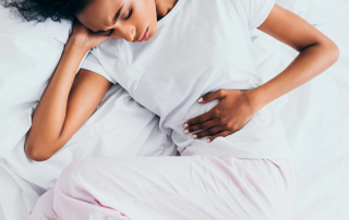 Woman laying on a bed holding her stomach.
