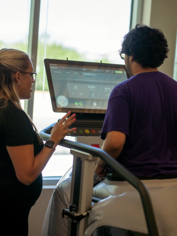 A therapist setting a man up to use a Boost treadmill.