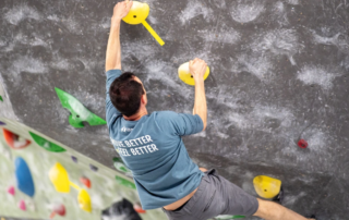 Derrick Debenedetto climbing an indoor rock wall.