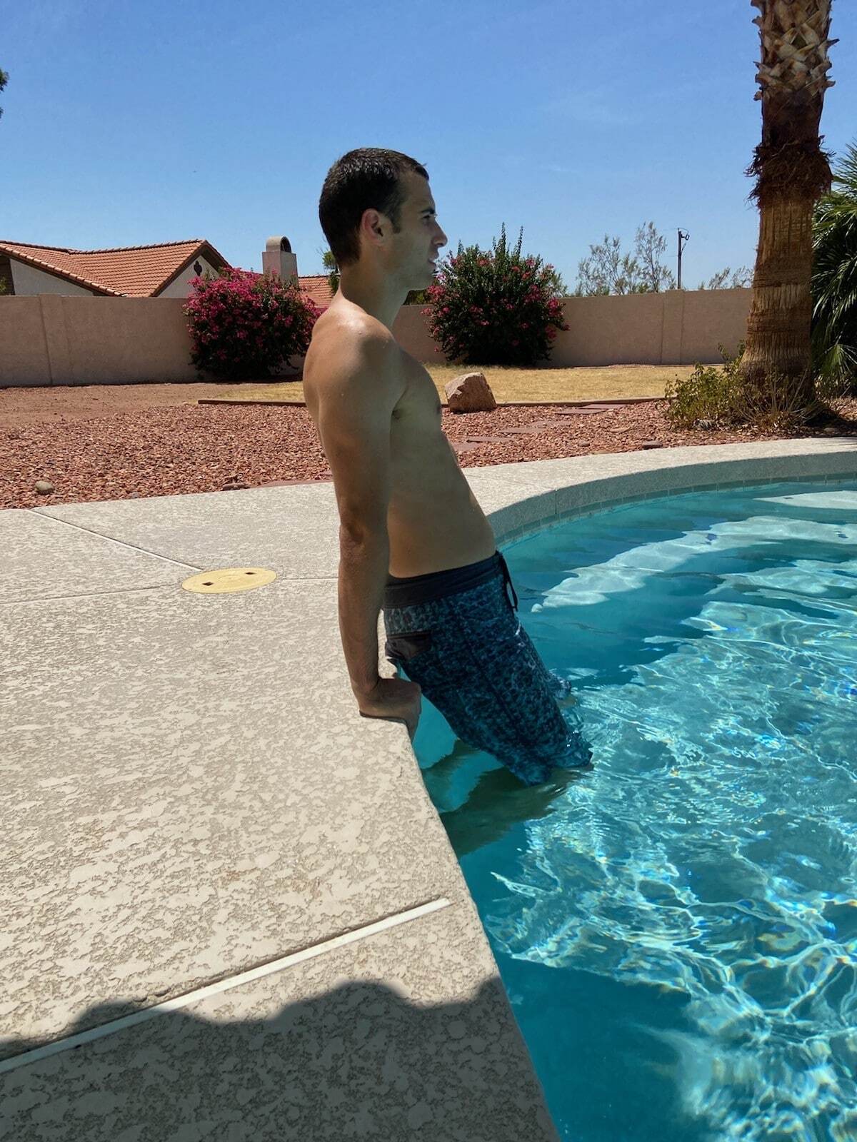 A man doing deck dips in a pool.
