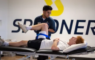A therapist performs knee manipulation on a young man.