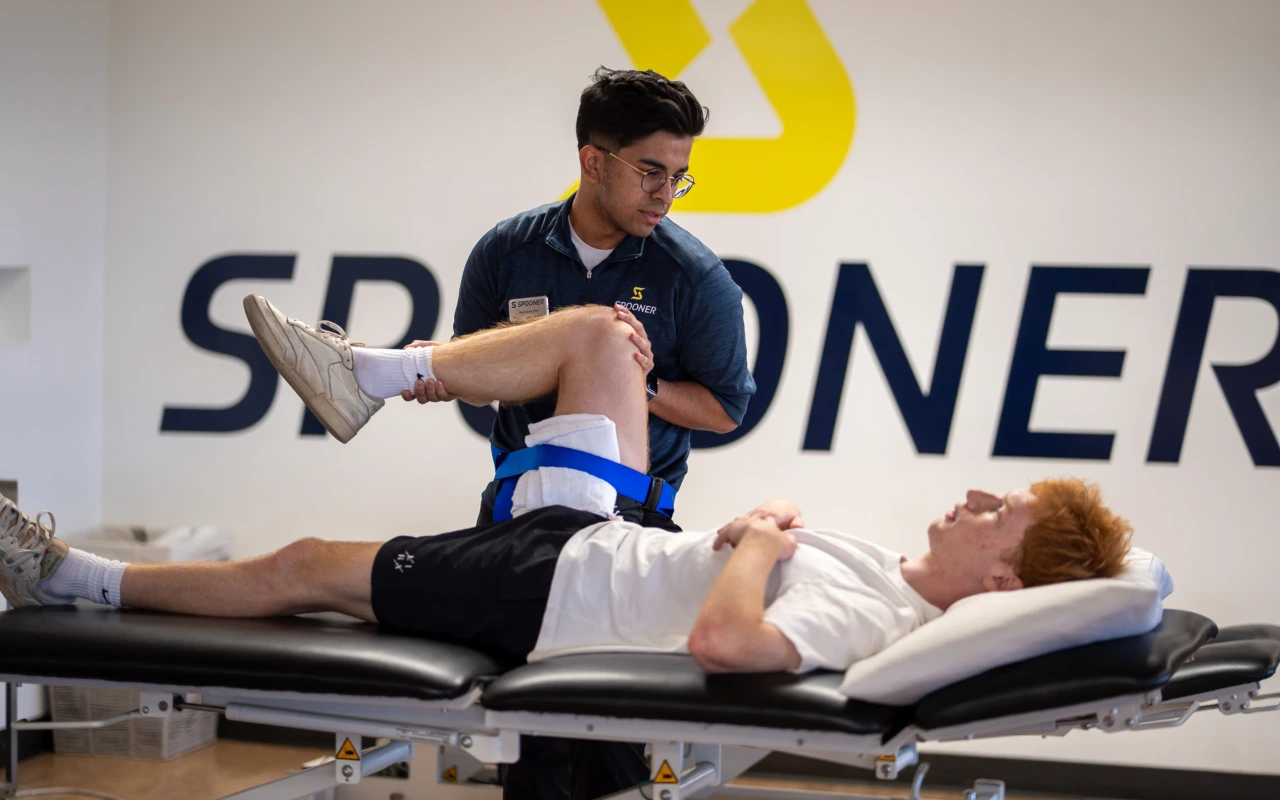 A therapist performs knee manipulation on a young man.