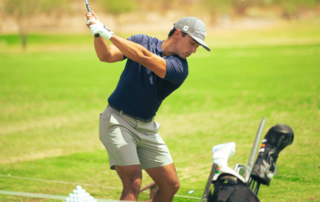 A man about to take a swing with a golf club on a putting green.