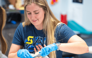 A hand therapist using an astym tool on a patient.