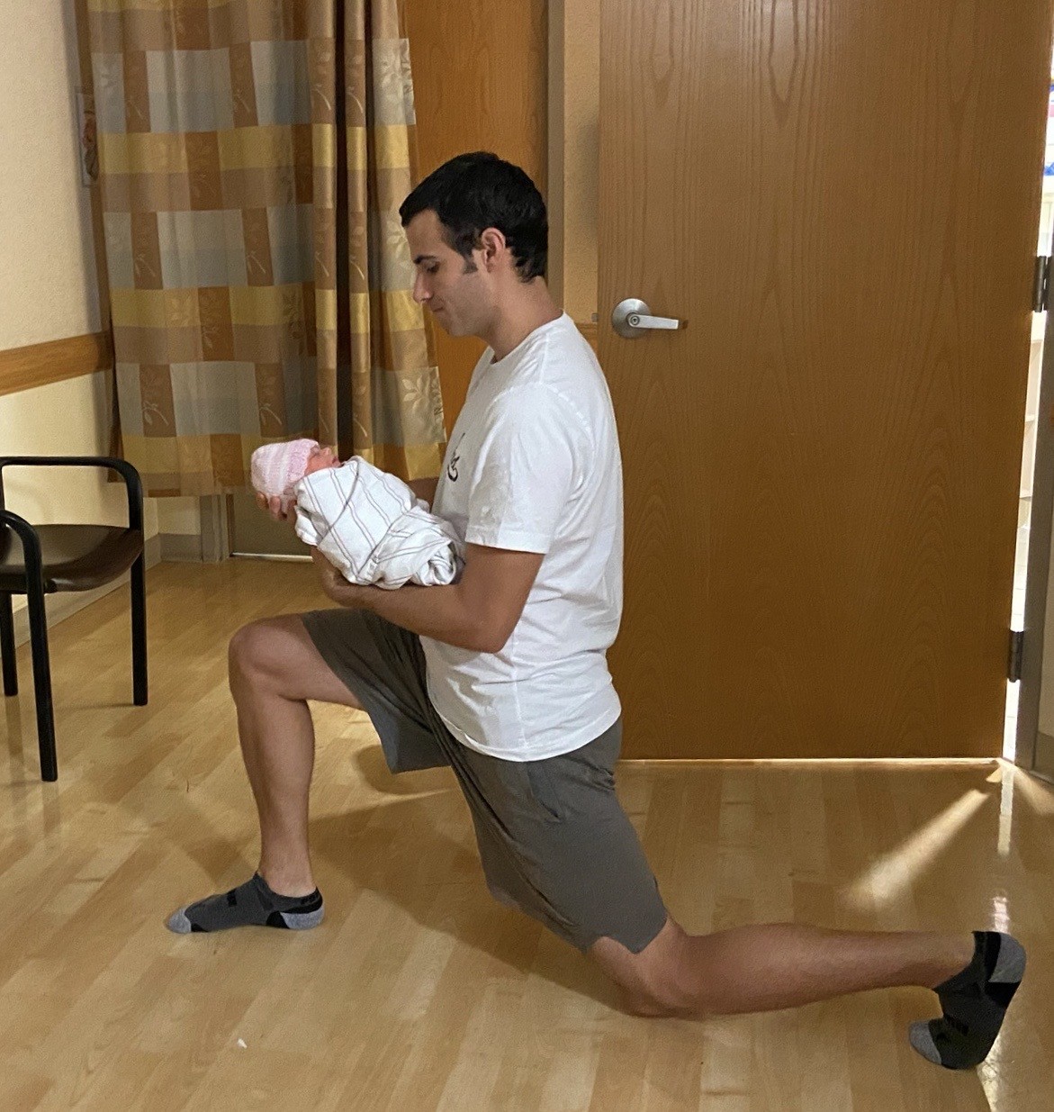 A new father does lunges while holding his baby.