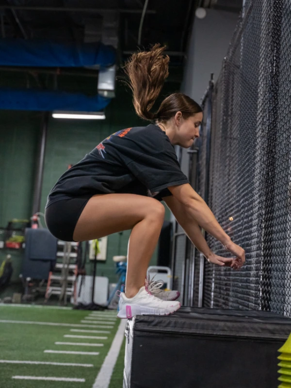 A teen athlete doing a high box jump.