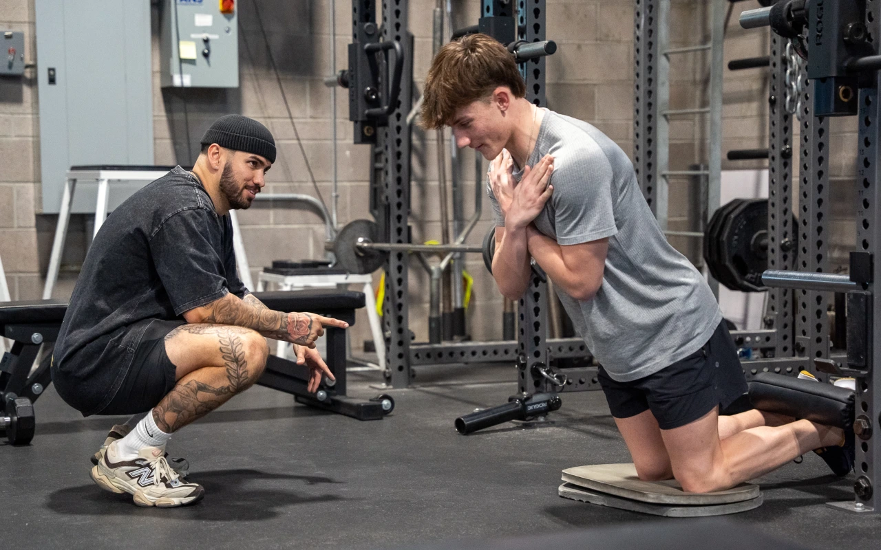 A teen athlete doing a nordic hamstring curl.