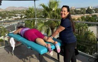 Maria Kline working on the leg of a woman laying facedown on a table.