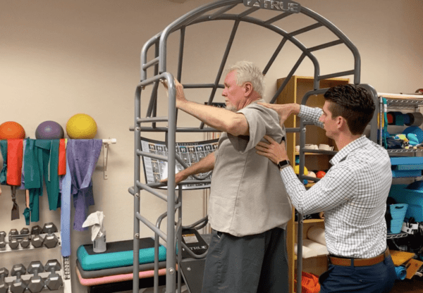 An older man stretching in a stretch cage for prehab treatment.