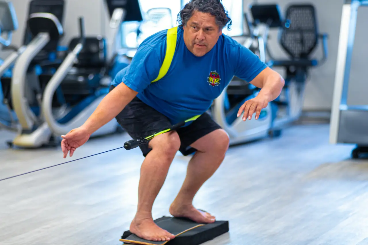 Man on a skateboard base sitting on top of a foam pad practicing his balance.