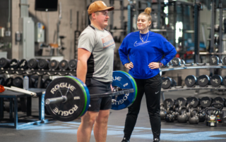 Kaitlyn Keyser, PT, DPT, SCS, ATC, CSCS with a male athlete as he performs deadlifts at the Spooner Sports Institute.
