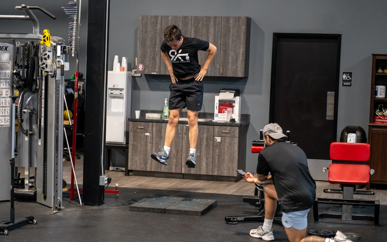 An athlete using a force plate while a athletic trainer measures the impact.