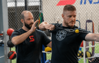 Image of Tanner Chitwood working with a crossbow athlete practicing pull back form