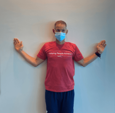 A man demonstrating wall angels step 2.