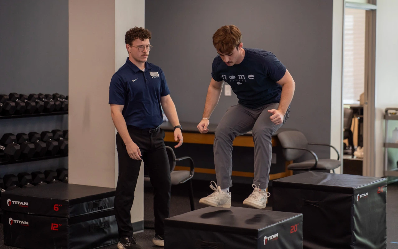 Payson training a wrestler as the wrestler jumps onto a plyometric box.