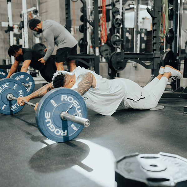 An athlete doing ab roll outs with a barbell.
