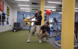 Feature image of a man getting tips on his golf swing from a physical therapist.