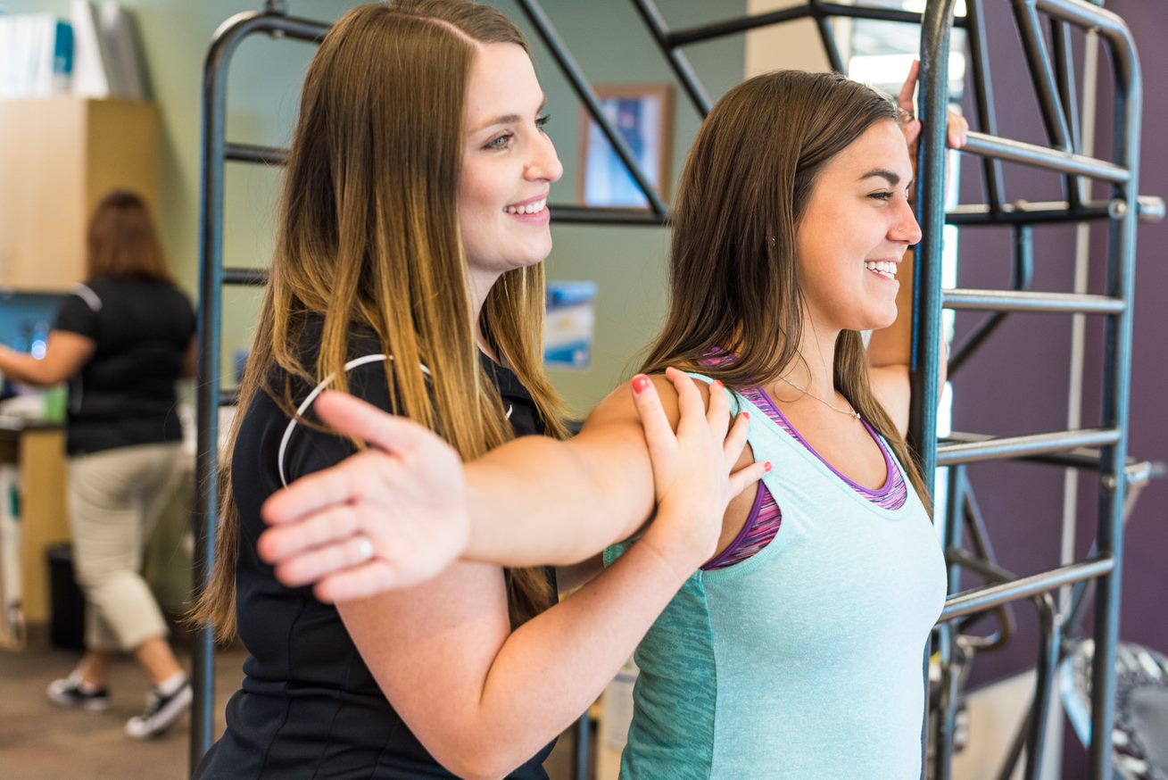 A woman and a physical therapist doing a chest stretch for breast cancer recovery.