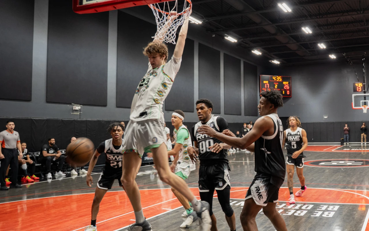 A basketball player slam dunks a basketball.