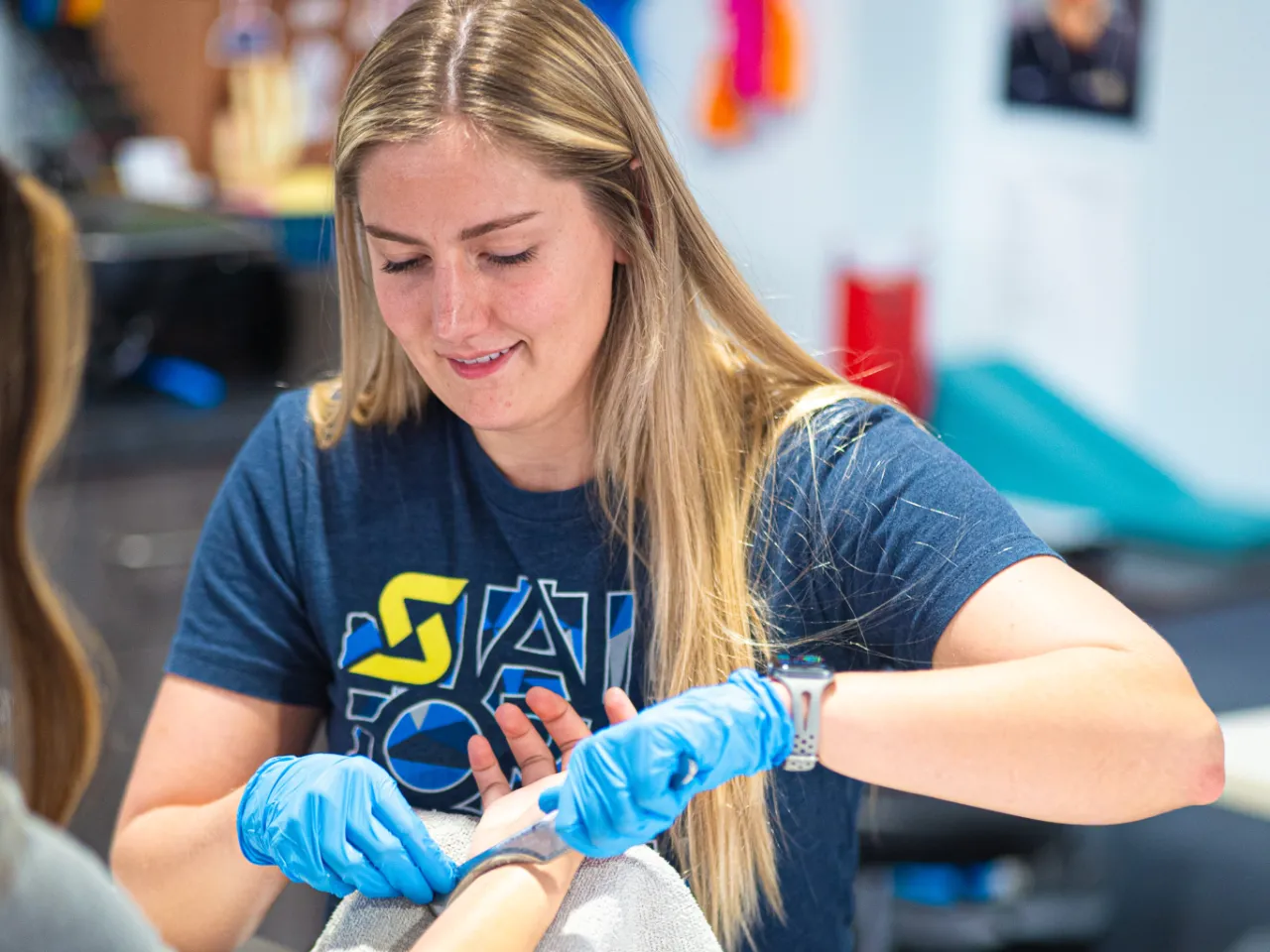 A hand therapist using an astym tool on a patient.