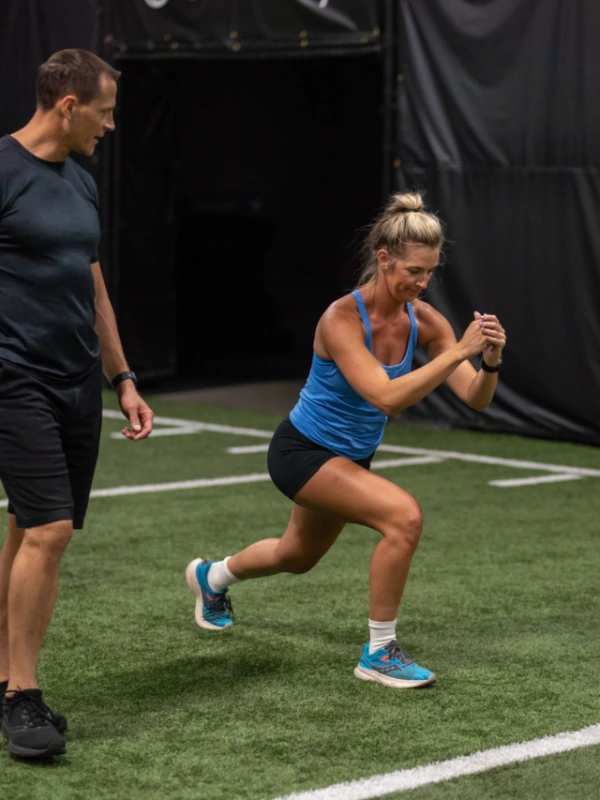 A woman doing lunges on an indoor turf.