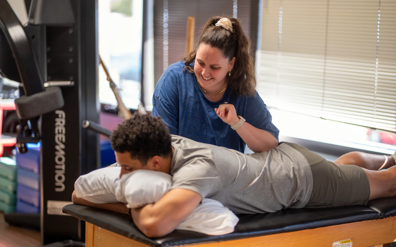 A physical therapist performing pelvic floor manipulation on a male athlete.