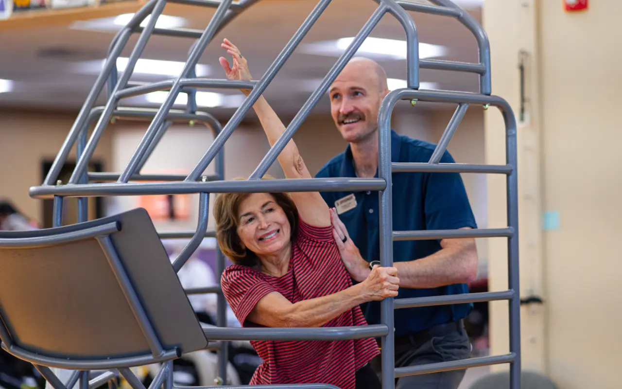John Kline helping a female patient stretch in a stretch cage.