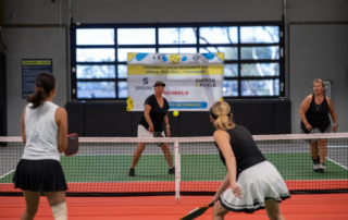 Four women playing pickleball indoors.
