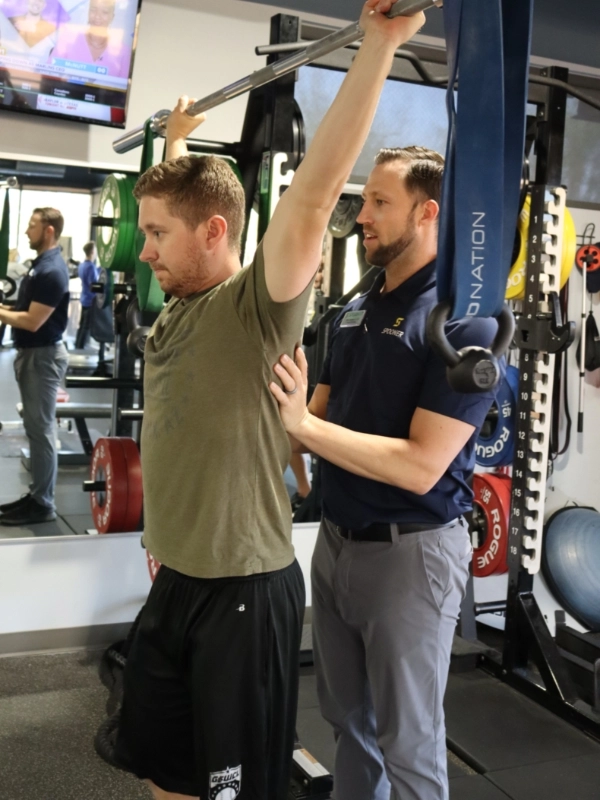 out-Ortho image 1 Image of a man holding a barbell over his head.