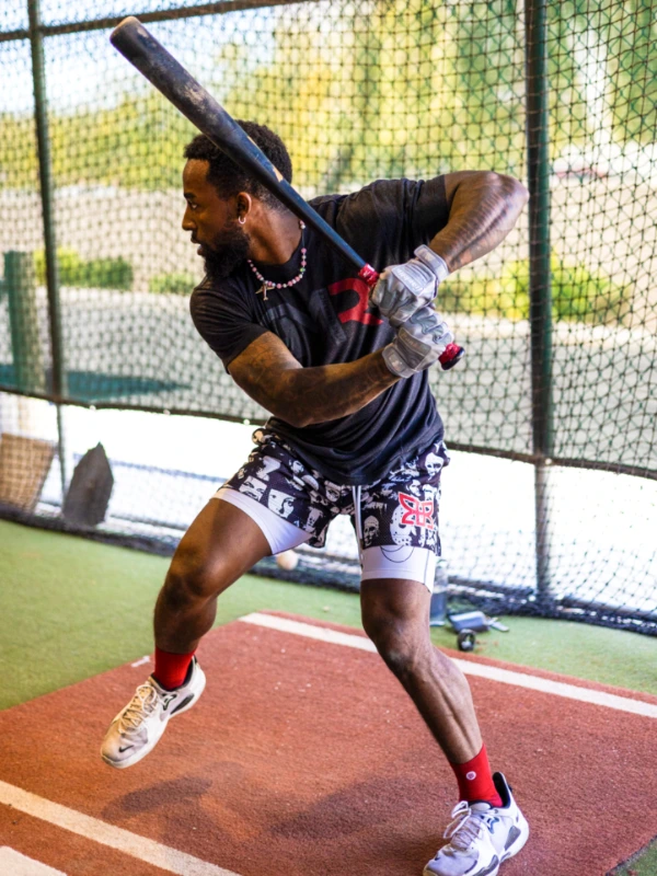 A MLB player winds up to swing a bat in a batting cage.