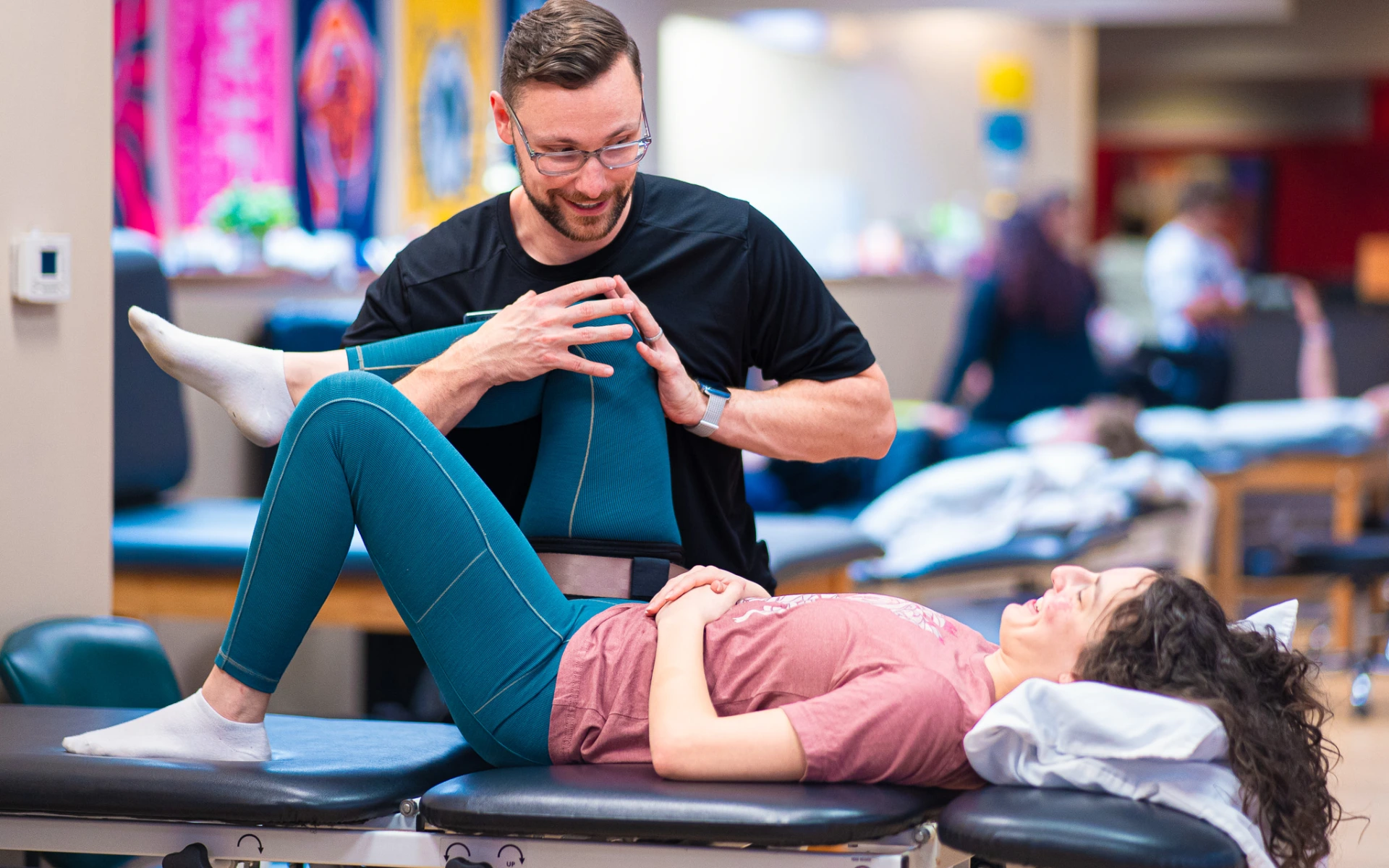 A female patient lays down on a table while Eric Brown works on her knee at the Spooner Ahwatukee location.