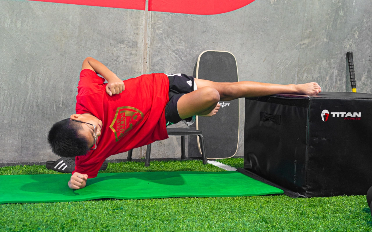 A young boy hold an elevated side plank.