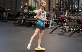 A teen athlete balancing on a wooden board.