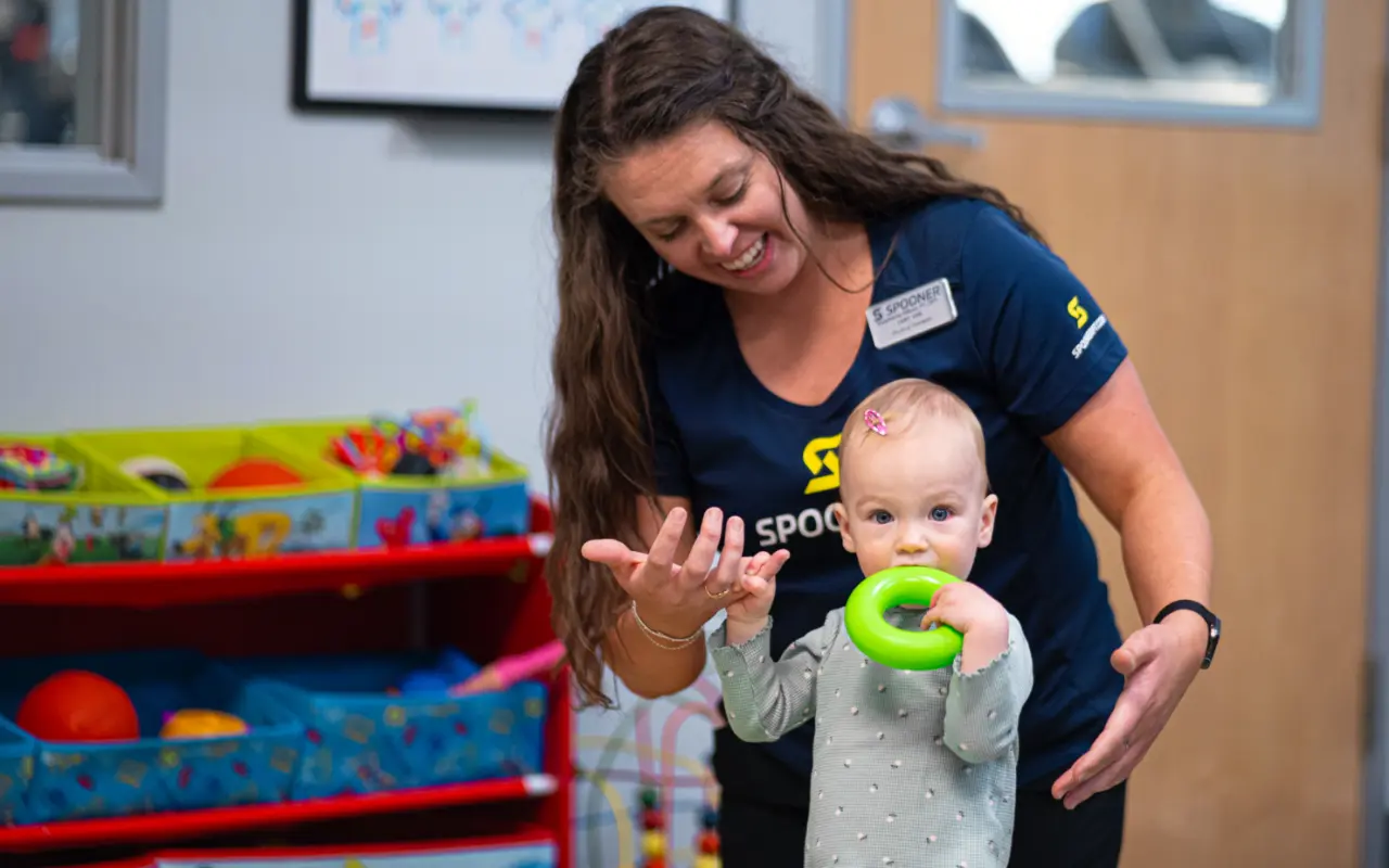 Stephanie Gilboy, PT, DPT, Cert. VRS plays with an infant with delayed developmental milestones holding a green ring.