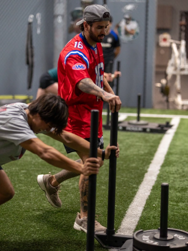 A male athlete pushing a weight sled.