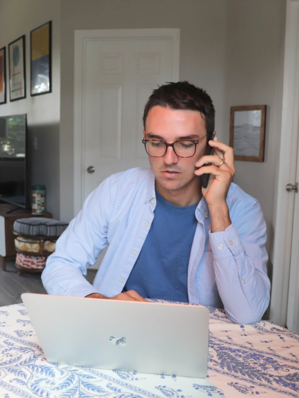 Image of a man on the phone as he looks at his computer.