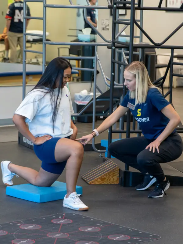 FIT page image 7 Image of a FIT trainer helping a woman do kneeling lunges.