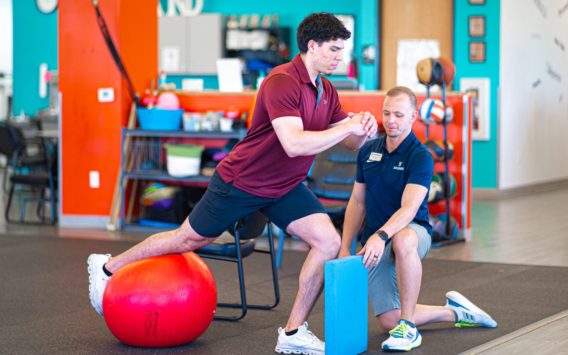 Tanner Caughey, PT, DPT treating a patient with patellar tendonitis as the patient lunges against a foam pad with a red exercise ball.