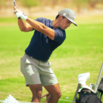 A man about to take a swing with a golf club on a putting green.