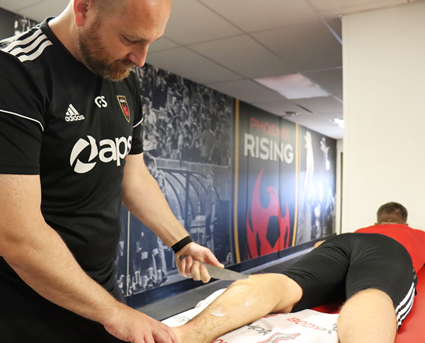A therapist performing soft tissue mobilization on a patient's leg.