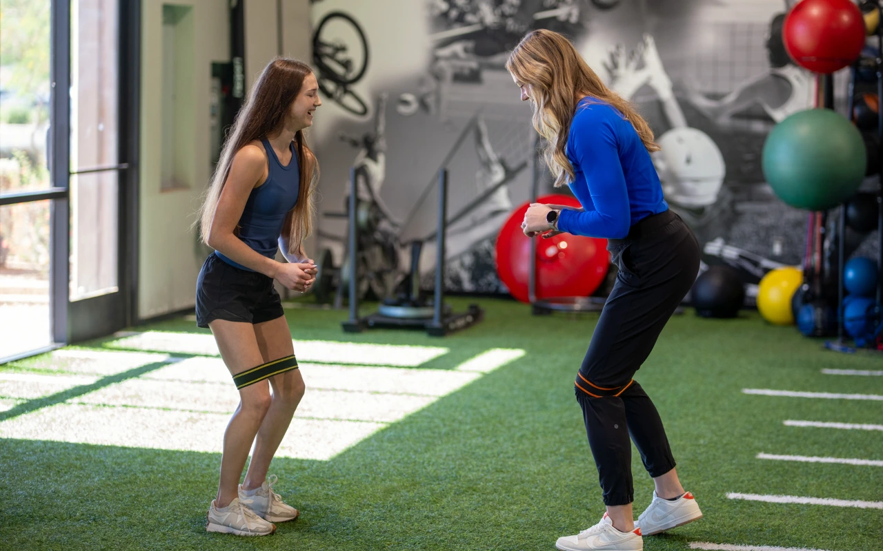 An female athlete doing a banded side walk with a physical therapist for gymnastic recovery.