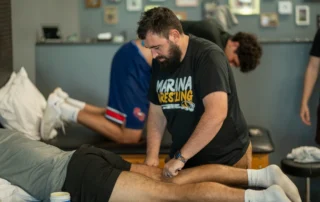 A physical therapist doing soft tissue mobilization on the hamstring of a male athlete.