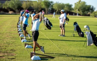 A row of golfers teeing up on the green.